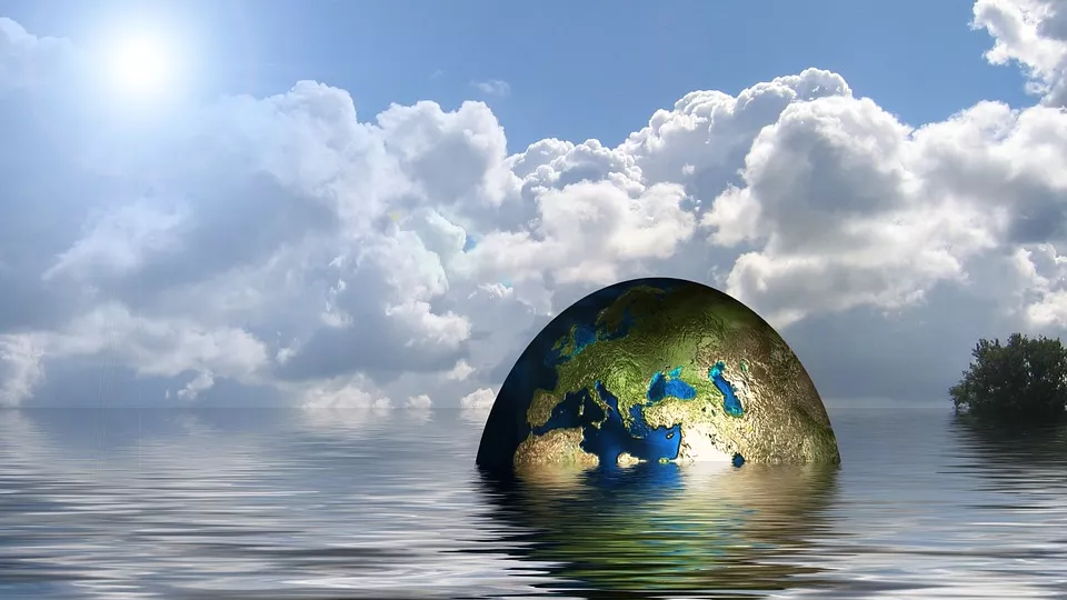 A globe half under the water surface and a cloudy but blue sky behind. Photocollage.