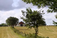 Fotografi på ett jordbrukslandskap med träd och ett hus