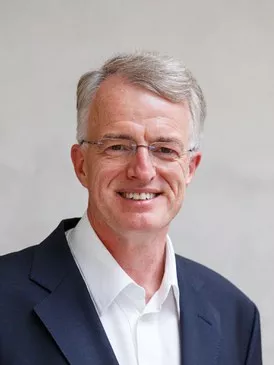Photo of Detlef Sprinz in a white shirt and blue jacket.